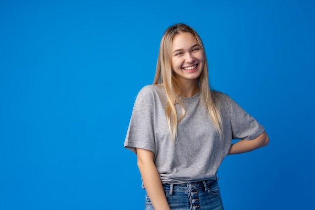 Gelukkig lachend mooie tienermeisje lachen over blauwe achtergrond, close-up