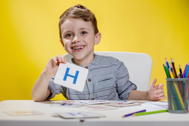 Gelukkig lachend preschool jongetje toont brieven thuis huiswerk maken op de ochtend voordat de school begint