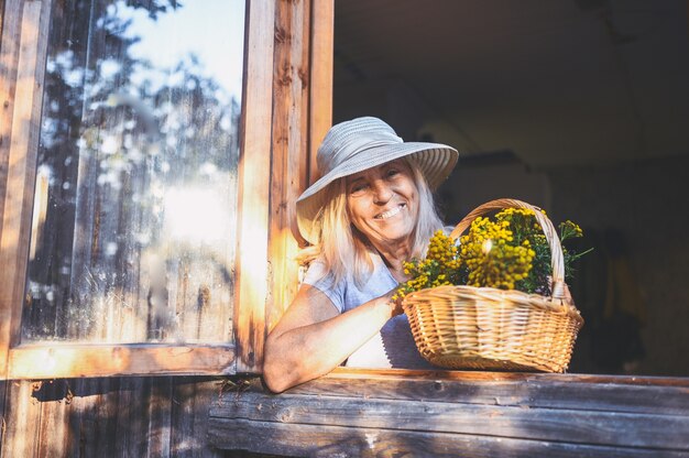 Gelukkig lachend senior vrouw poseren met bloemen