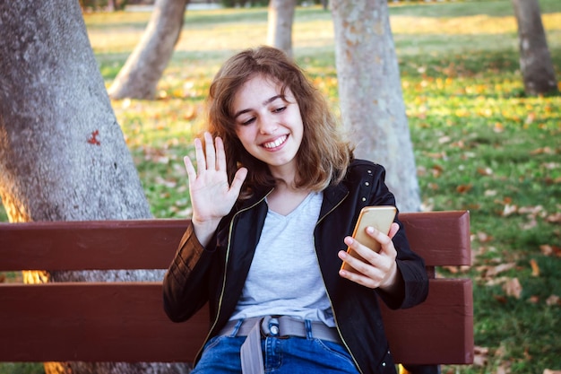 Gelukkig lachend tienermeisje chatten met vrienden via video-oproep op smartphone. Meisje groet vrienden