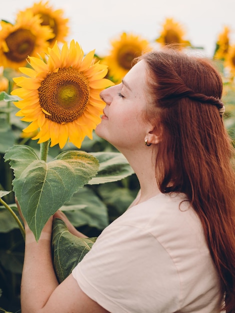 Gelukkig lachend vrouwtje staande in zonnebloemen veld op zomerdag Oogsttijd Zomervakantie