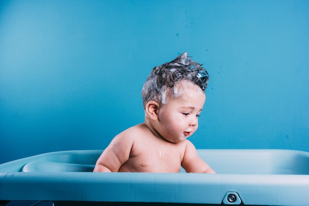 Gelukkig lachende baby die een bad neemt Glimlachend kind in de badkamer