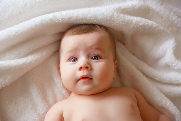 Gelukkig lachende baby in een handdoek na het baden