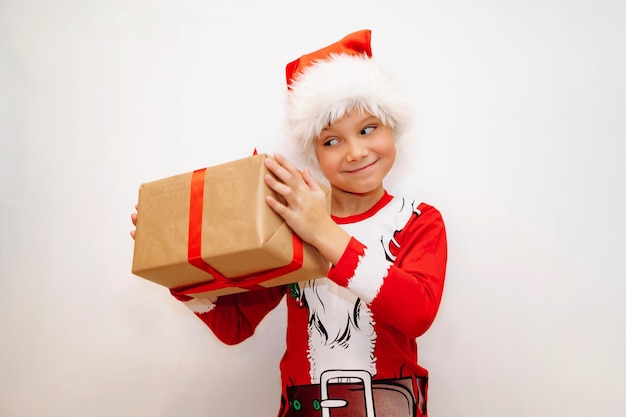 Gelukkig lachende blanke jongen in santa t-shirt en hoed met een pokken met kerstcadeau