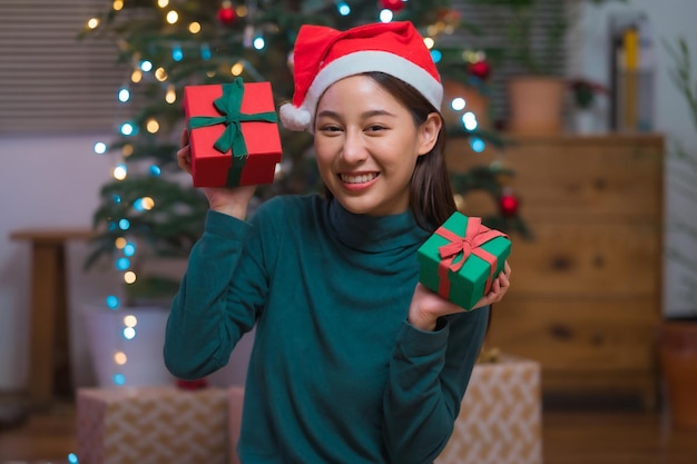 Gelukkig lachende jonge Aziatische vrouw in de hoed van de kerstman met veel geschenkdoos vieren Kerstmis en nieuwjaar