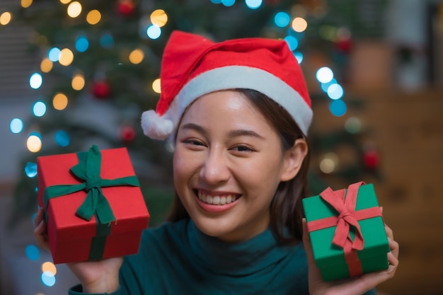 Gelukkig lachende jonge aziatische vrouw in de hoed van de kerstman met veel geschenkdoos vieren kerstmis en nieuwjaar