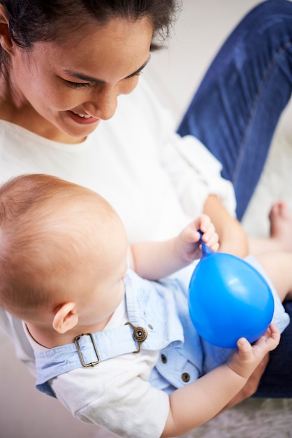 Gelukkig lachende jonge moeder knuffelen haar zoontje spelen met blauwe ballon wanneer ze samen tijd doorbrengen thuis