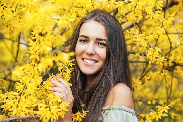 Gelukkig lachende jonge vrouw met lentebloemen in de tuin