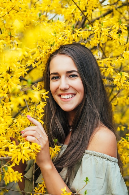 Gelukkig lachende jonge vrouw met lentebloemen in de tuin