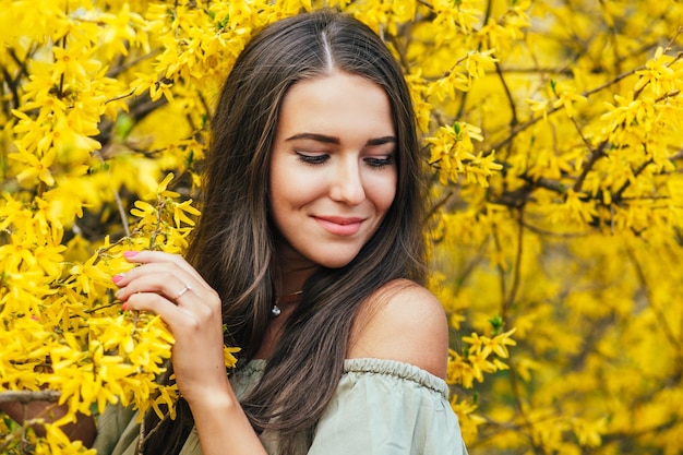 Gelukkig lachende jonge vrouw met lentebloemen in de tuin