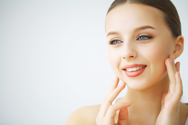 Gelukkig lachende jonge vrouw met perfecte huid, natuurlijke make-up en een mooie glimlach. Vrouwelijk portret met blote schouders