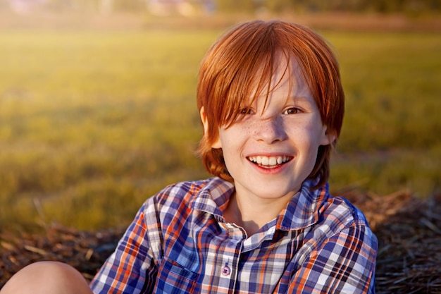 Foto gelukkig lachende jongen met rood haar en sproeten in het veld portret van ongeveer 8 jaar oude zomertijd