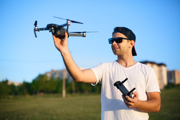 Gelukkig lachende man houdt kleine compacte drone en afstandsbediening in zijn handen pilootlanceringen