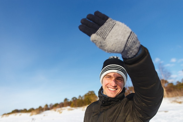 gelukkig lachende man in jas en winter hoed genieten van zonnige winterdag.