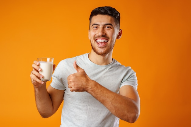 Gelukkig lachende man met melk tegen geel