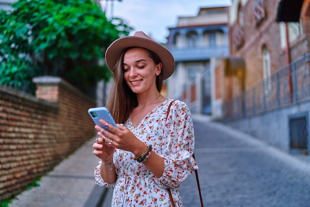 Gelukkig lachende mooie schattige vrolijke jonge meisjesreiziger die smartphone gebruikt tijdens het vakantieweekend tijdens het bezoeken van bezienswaardigheden