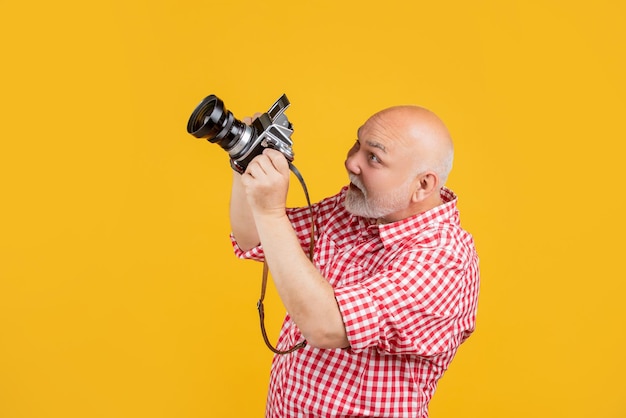 Gelukkig lachende oude man met retro fotocamera op gele baqckground