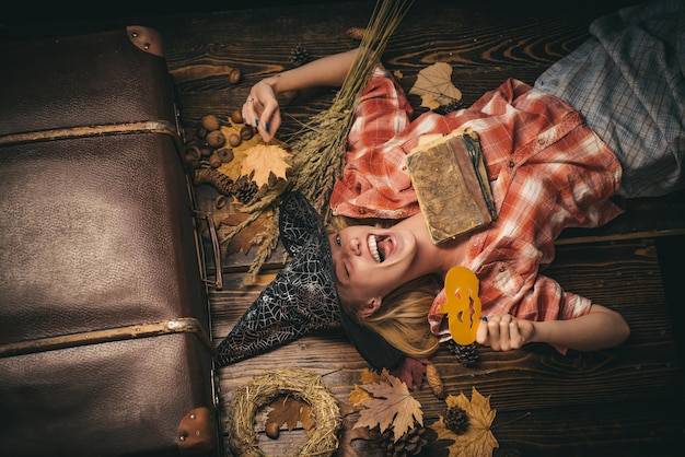 Gelukkig lachende vrouw op Halloween achtergrond. Fijne Halloween. Halloween-heks met een gesneden pompoen.