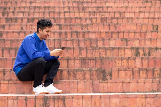 Gelukkig Latijns-man chatten op zijn smartphone. Patroon van oranje trappen