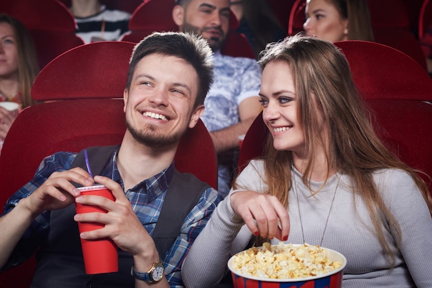 Gelukkig leuk paar dat popcorn eet en bij grappige komedie in bioskooptheater lacht. Aantrekkelijk meisje en knap met romantische date en genieten van interessante film. Concept van entertainment.