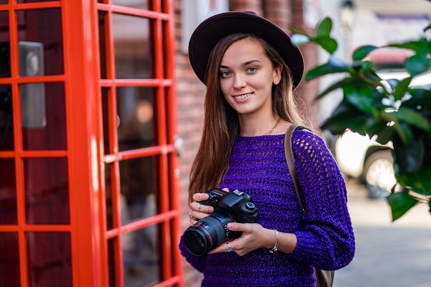 Gelukkig leuke aantrekkelijke jonge vrouw fotograaf in hoed met camera tijdens een wandeling door de stad
