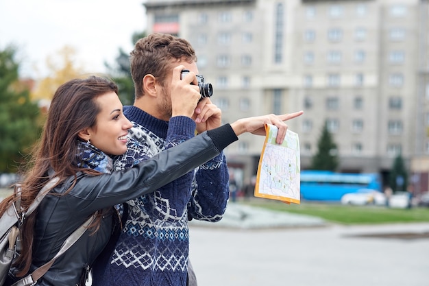 Gelukkig liefdespaar toeristen die foto's nemen op excursie of stadstour. Reis samen met een kaart en retro camera