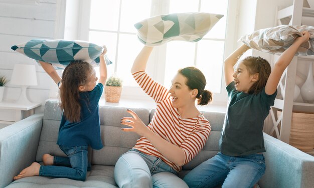 Gelukkig liefdevol gezin! De moeder en haar kinderen, meisjes, vechten met kussens.