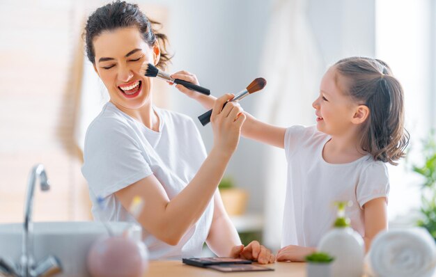 Gelukkig liefdevol gezin. Moeder en dochter doen make-up en hebben plezier.