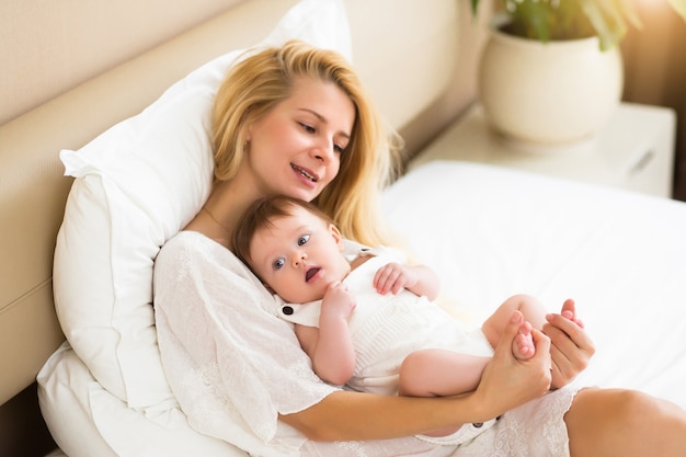 Gelukkig liefdevol jong gezin. moeder speelt met haar baby in de slaapkamer, hoge hoekmening.