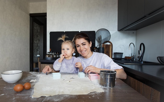 Gelukkig liefdevolle familie samen bakkerij koken. Moeder en dochter-meisje koken koekjes en hebben plezier in de keuken. Zelfgemaakt eten en een kleine helper.