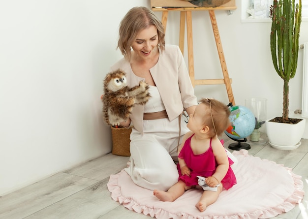 Gelukkig liefhebbend gezin moeder en dochtertje in de kinderkamer leuke moeder en mooie baby hebben plezier en spelen met uilpop