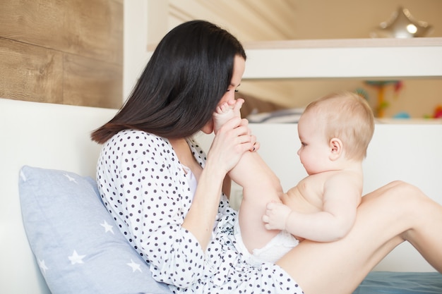 Gelukkig liefhebbende familie. moeder speelt met haar baby in de slaapkamer