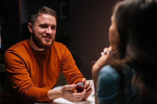 Gelukkig liefhebbende jonge man die een huwelijksaanzoek doet met een onherkenbare mooie vrouw die aan tafel zit met kaarsen, trouw met me