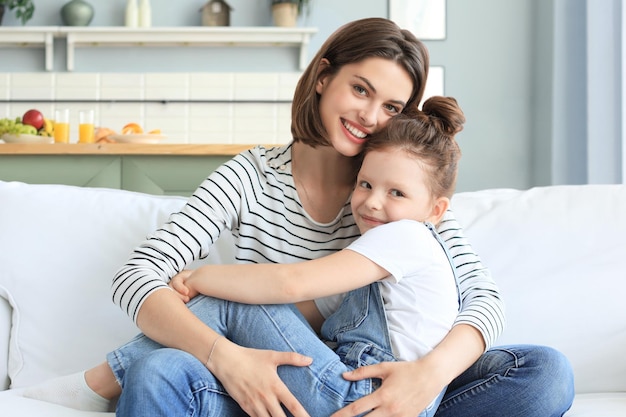 Gelukkig liefhebbende moeder die dochtertje knuffelt, tijd samen thuis doorbrengt.