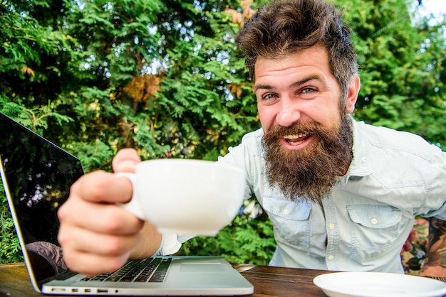 Foto gelukkig man aan het werk op laptop. brutale bebaarde hipster bij koffiepauze. kantoormedewerker. succesvolle zakenman. wendbaar bedrijf. zakelijk succes. perfecte deal. grote beslissingen nemen.