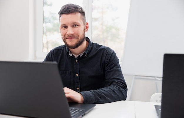 Gelukkig man aan het werk op laptop in kantoor