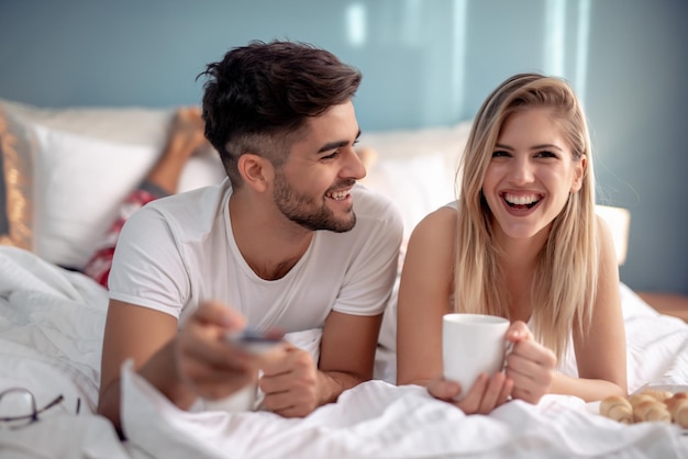 Gelukkig man en vrouw drinken koffie in bed