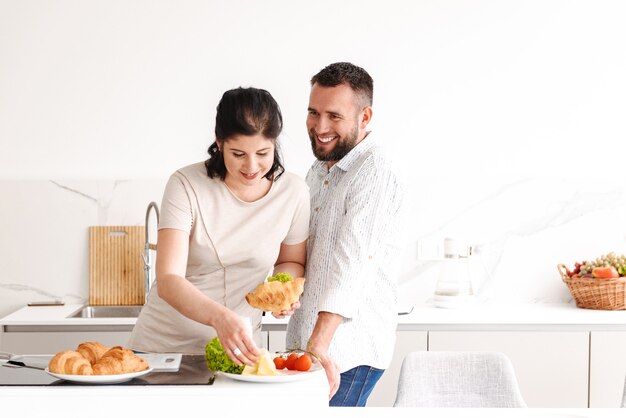 gelukkig man en vrouw koken, en ontbijten in lichte keuken