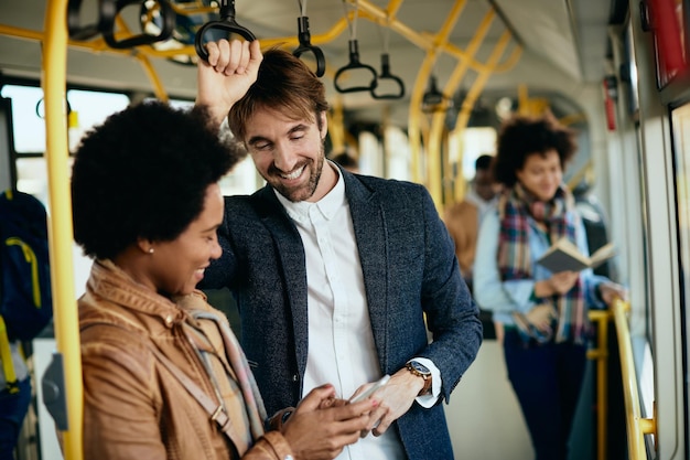 Gelukkig man en zijn zwarte vriendin met behulp van mobiele telefoon in een stadsbus