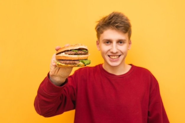 Gelukkig man in casual kleding heeft een smakelijke hamburger in zijn handen