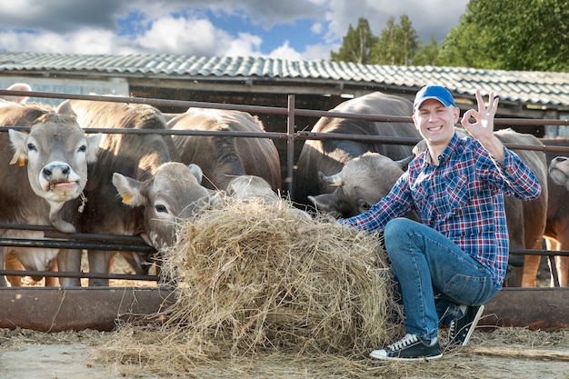 Foto gelukkig man in koeienboerderij toont ok teken van de hand