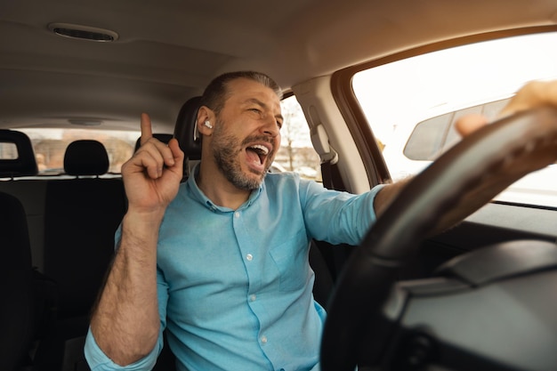 Gelukkig man in koptelefoon genieten van muziek rijden luxe auto