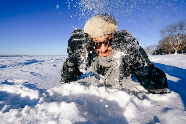 Gelukkig man in zonnebril buiten spelen met sneeuw