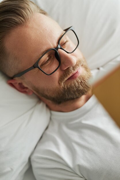 Gelukkig man met boek rustend op bed