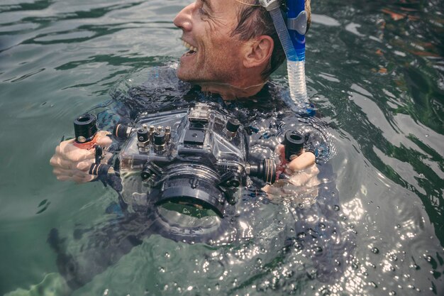 Foto gelukkig man met onderwater dslr cameratas in een meer