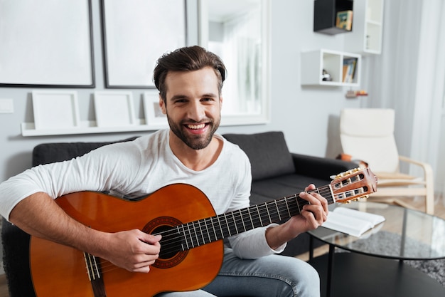 Gelukkig man spelen op gitaar. Camera kijken.