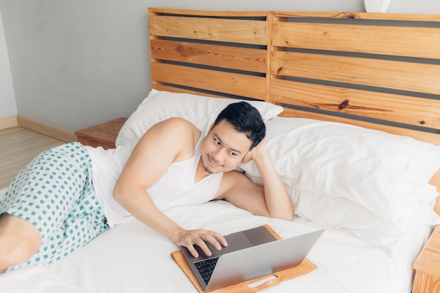 Gelukkig man werkt met zijn laptop op zijn bed. concept freelancer succesvolle levensstijl.