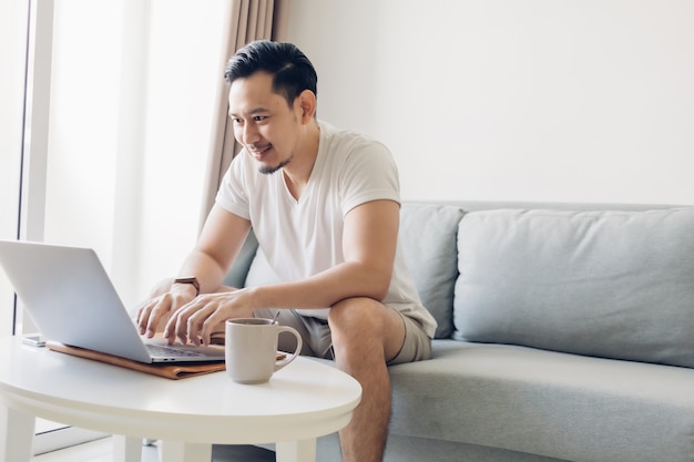 Gelukkig man werkt op zijn laptop in de woonkamer.