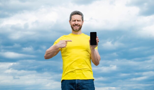 Gelukkig man wijs vinger op scherm van smartphone met kopieerruimte