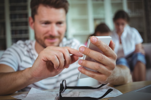 Gelukkig man zittend aan tafel en het gebruik van zijn mobiele telefoon